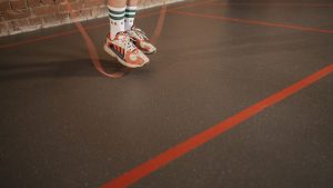 Feet of a person in sneakers skipping rope on an indoor gym floor.