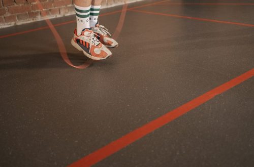 Feet of a person in sneakers skipping rope on an indoor gym floor.