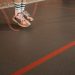 Feet of a person in sneakers skipping rope on an indoor gym floor.